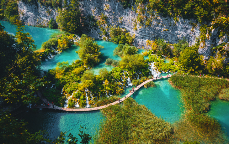© Leonid Tit - stock.adobe.com - Luftaufnahme eines hölzernen Wanderwegs neben Wasserfällen im Nationalpark Plitvicer Seen