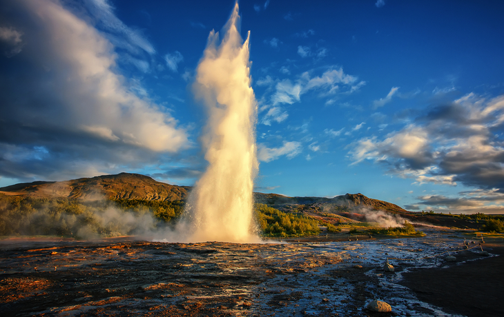 © jenyateua - stock.adobe.com - Ausbruch des Strokkur-Geysirs in Island bei Sonnenuntergang
