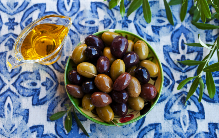 Sortiment frischer Oliven auf einem Teller mit Olivenbaum-Brunch. Blauer Textilhintergrund. Ansicht von oben. - © annapustynnikova - stock.adobe.com