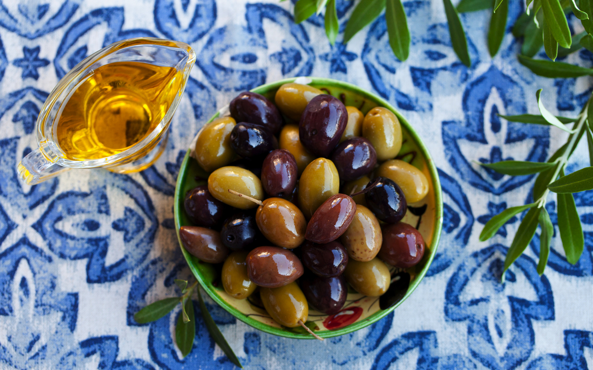 Sortiment frischer Oliven auf einem Teller mit Olivenbaum-Brunch. Blauer Textilhintergrund. Ansicht von oben. - © annapustynnikova - stock.adobe.com