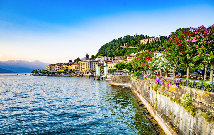 Blick auf einen malerischen See mit Blumen und Bergen im Hintergrund. - © SeaRain - stock.adobe.com