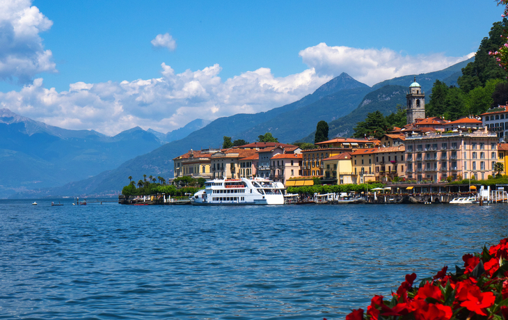 Blick auf einen malerischen See mit Blumen und Bergen im Hintergrund. - © SeaRain - stock.adobe.com