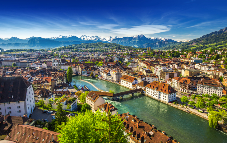 Panoramablick von einem Berg über einen See und eine Stadt bei klarem Himmel. - © djama - stock.adobe.com