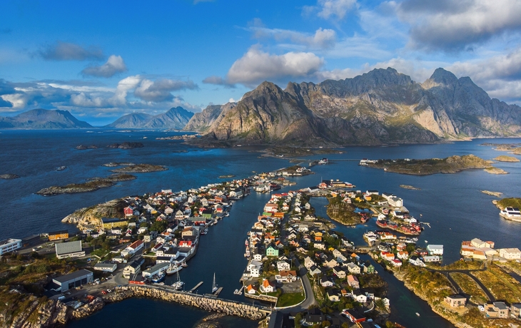 Rote Holzhäuser am Fjord mit Bergen im Hintergrund unter blauem Himmel - © Jamo Images - stock.adobe.com