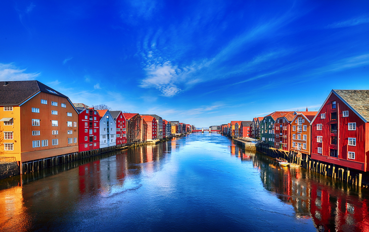 Bunte Häuser entlang des Trondheimer Fjords in Trondheim, Norwegen, unter klarem blauem Himmel. - © Piotr Krzeslak - stock.adobe.com
