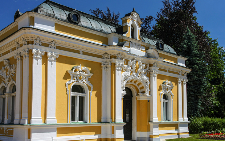 Gelbes historisches Gebäude mit verzierten weißen Details und großem Eingangsportal. - © Michael - stock.adobe.com