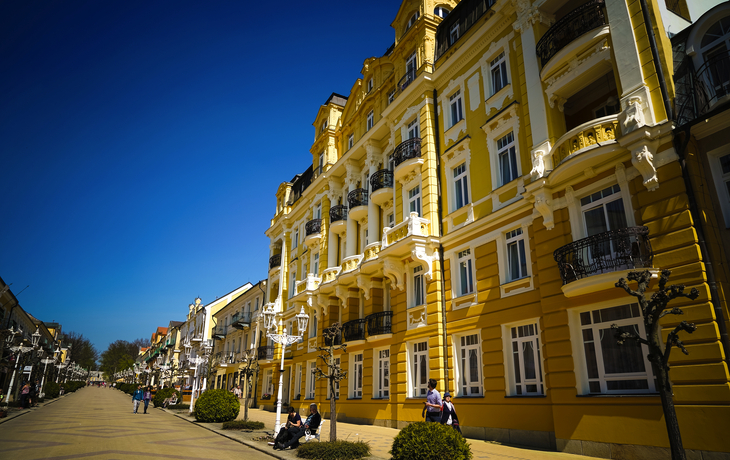 Gelbes historisches Gebäude mit verzierten weißen Details und großem Eingangsportal. - © Michael - stock.adobe.com