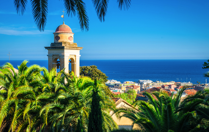 Glockenturm vor der Kulisse von Sanremo an der ligurischen Küste mit Blick auf das Meer und Palmen. - © anilah - stock.adobe.com