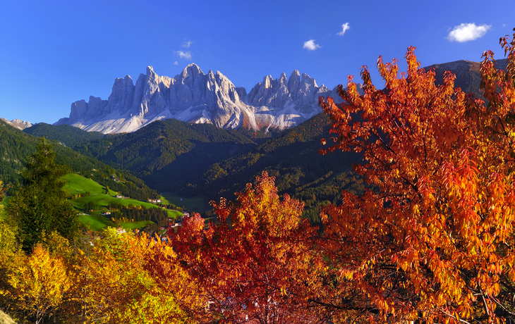 Berglandschaft mit Hütten bei Sonnenuntergang, Dolomiten im Hintergrund. - © rolandbarat - stock.adobe.com