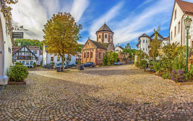 Historischer Platz mit gelben Gebäuden, Sonnenschirmen und Palmen bei klarem Himmel. - © EKH-Pictures - stock.adobe.com