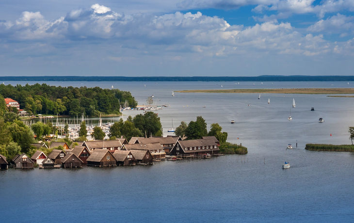 Landschaft mit See, Booten und Ufergebäuden unter bewölktem Himmel. - © Heiko Zahn - stock.adobe.com
