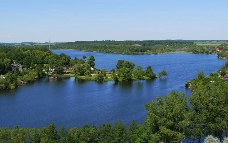 Landschaft mit See, Booten und Ufergebäuden unter bewölktem Himmel. - © Heiko Zahn - stock.adobe.com