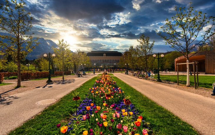 Garten mit blühenden Blumen im Vordergrund und monumentalem Gebäude im Hintergrund. - © lexpixelart - stock.adobe.com
